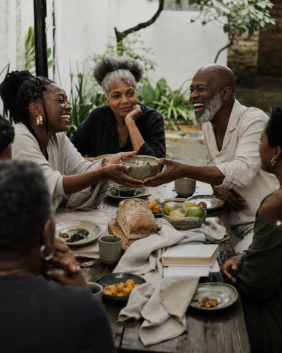 Friends across generations passing a bowl at a shared outdoor table